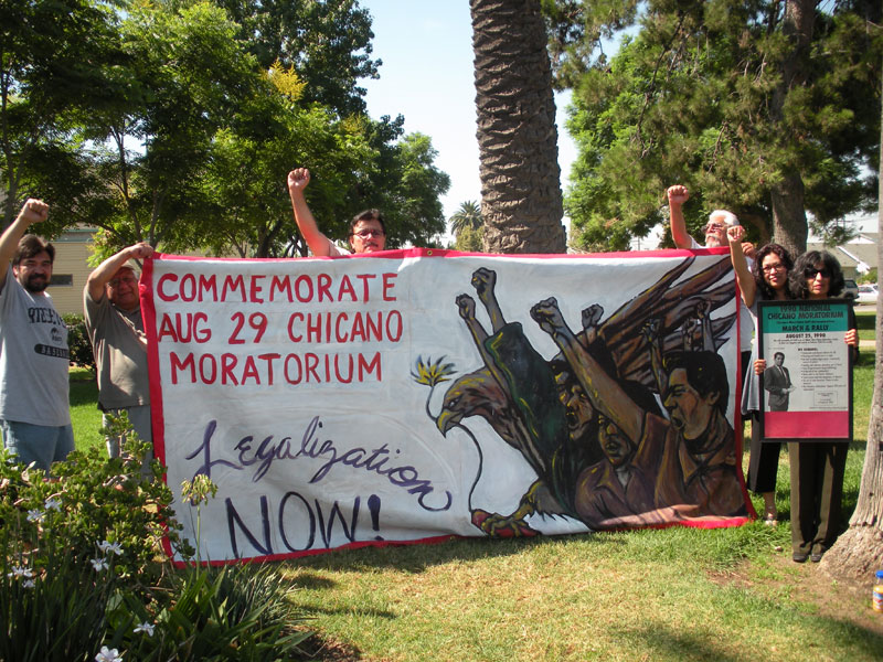 Activists raise a banner commemorating the August 29 Chicano Moratorium